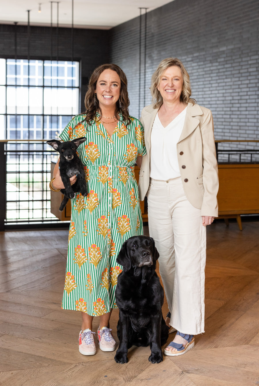 Two women smiling with two black dogs in a modern interior